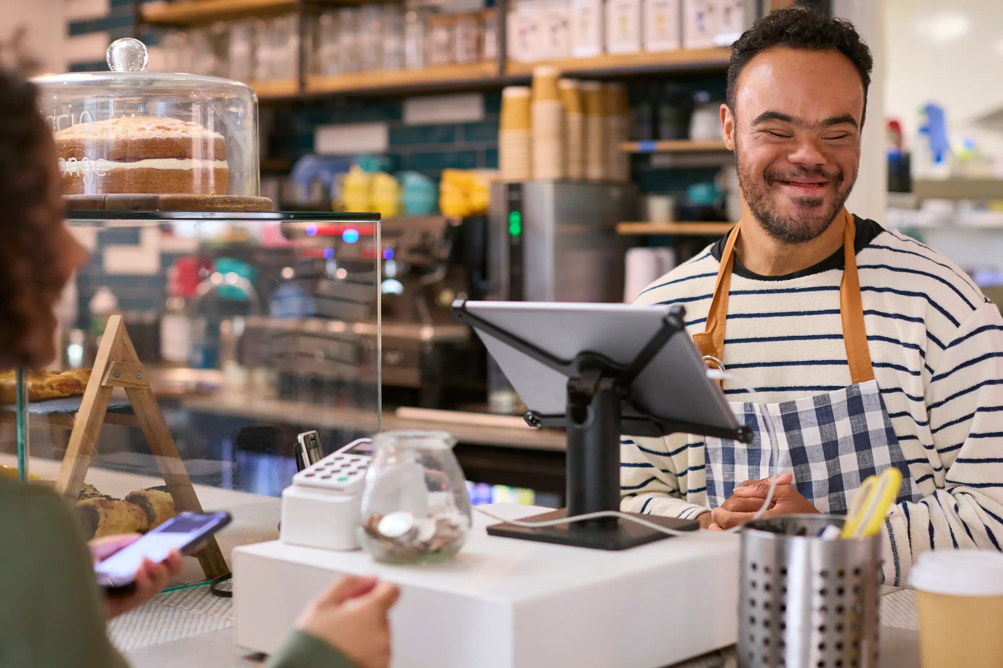 Friendly barista serving coffee with a smile behind the counter.